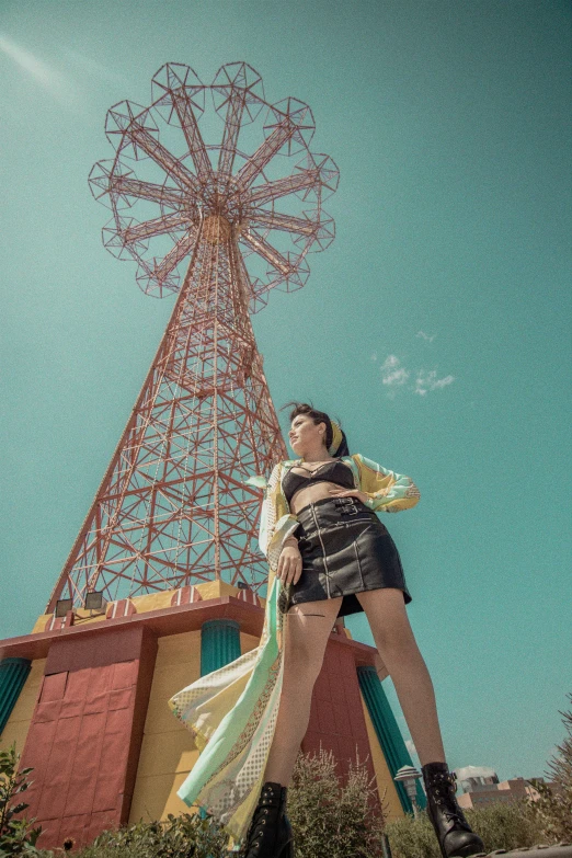 a woman standing in front of a radio tower, a portrait, by Ric Estrada, pexels contest winner, magic realism, ferris wheel, cinematic outfit photo, red and teal and yellow, sunny day time