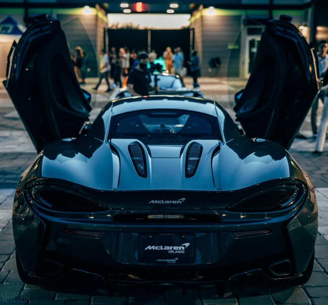 a black sports car parked in front of a building, by Sam Dillemans, pexels contest winner, mclaren, with his back turned, festivals, 15081959 21121991 01012000 4k