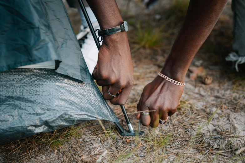 a person holding a pair of scissors next to a tent, by Matija Jama, trending on unsplash, visual art, intricate african jewellery, frying nails, covering the ground, thumbnail