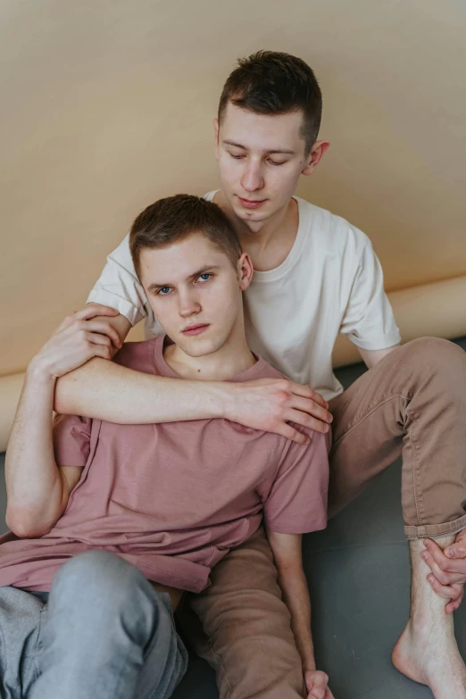 a couple of men sitting on top of a bed, by Attila Meszlenyi, trending on pexels, renaissance, 1 7 - year - old boy thin face, holding each other, soft rubber, genderless
