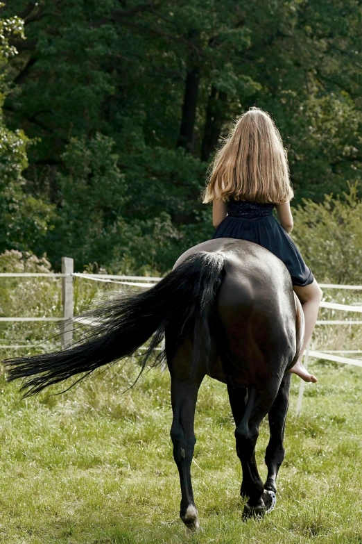 a little girl rides her horse while standing in the field