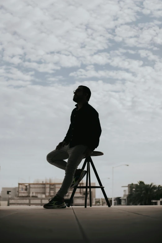 a man in black is standing on a stool with his legs crossed