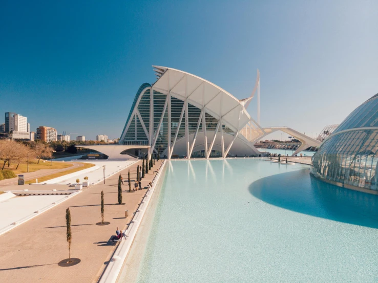 a long pool near some large buildings and a blue sky