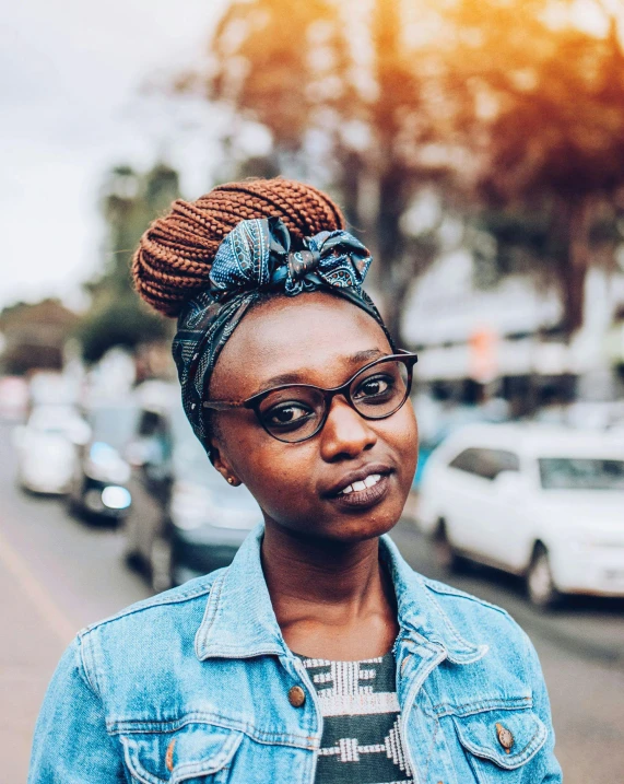 a black woman wearing a denim jacket and glasses with an afro on top