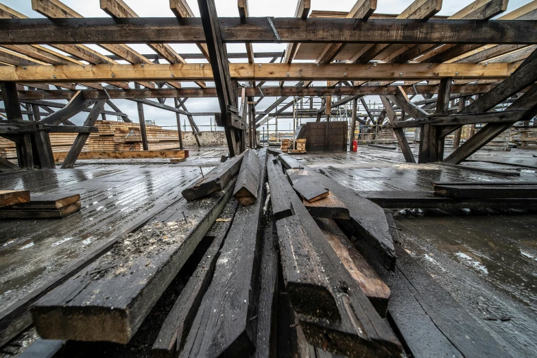 a pile of wood sitting on top of a wooden floor, by Tobias Stimmer, unsplash, renaissance, shipyard, buildings covered in black tar, thumbnail, preserved historical