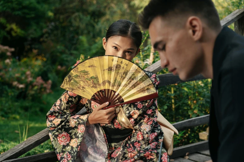 a man is standing with a woman holding a fan