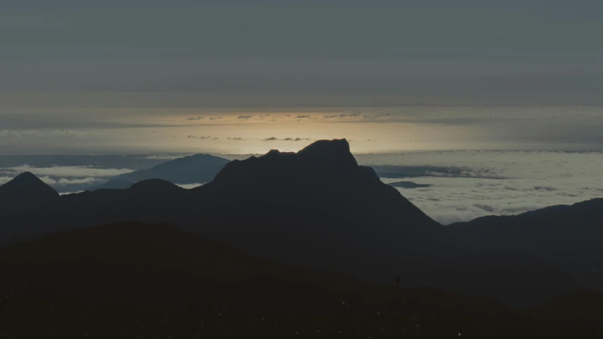 the sun shines behind mountains and clouds