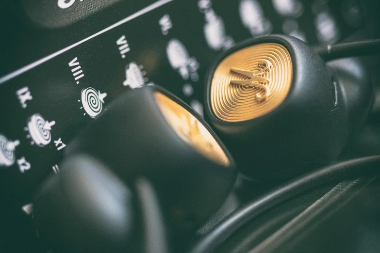 a pair of headphones sitting on top of a keyboard, a macro photograph, inspired by Harry Haenigsen, unsplash, purism, closeup of car engine, gold and black color scheme, button potenciometers, retro colour