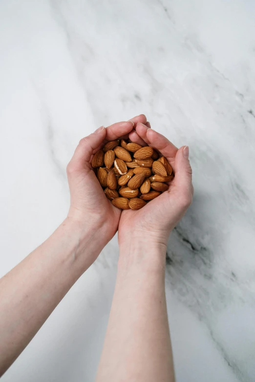 a person holding a handful of almonds in their hands, inspired by David Allan, product photo, evenly spaced, petite, pale smooth