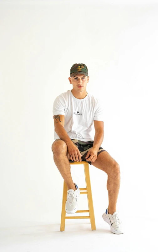 a young man sitting on top of a wooden stool