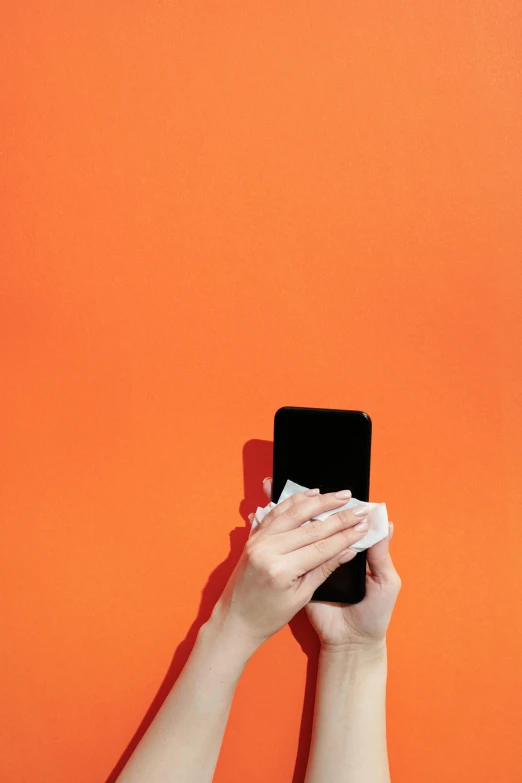 a person holding a cell phone up to their face, pexels, minimalism, orange and black, wash, square, paper