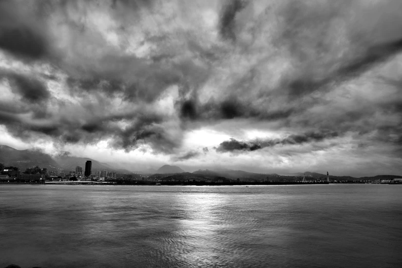 a cloudy sky over the ocean with a city in the distance