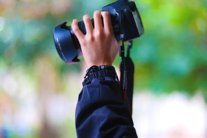 a person taking a picture with a camera, holding a stuff, short telephoto, colour photo, over-shoulder shot