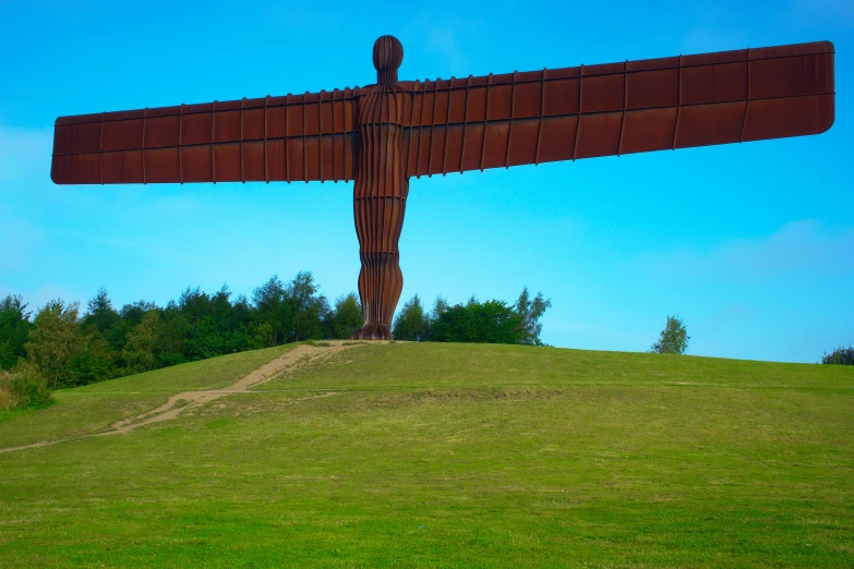 a large metal angel statue sitting on top of a lush green field, by John Henderson, giant axe, 2022 photograph, bridge, reddish