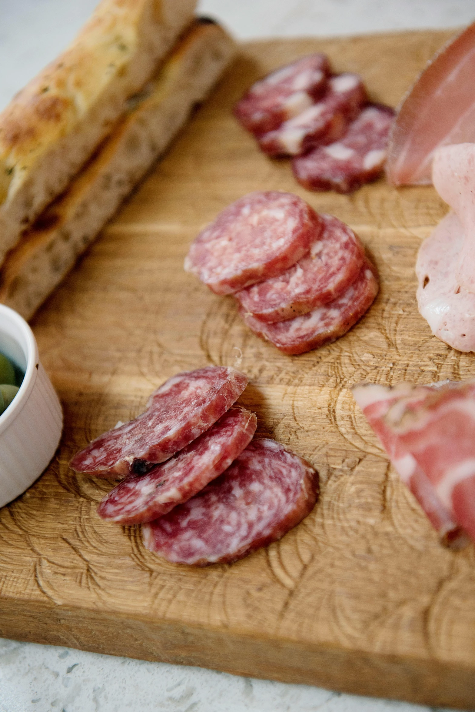 a wooden cutting board topped with meat and veggies, salami, brown bread with sliced salo, jamie hewlet, posh