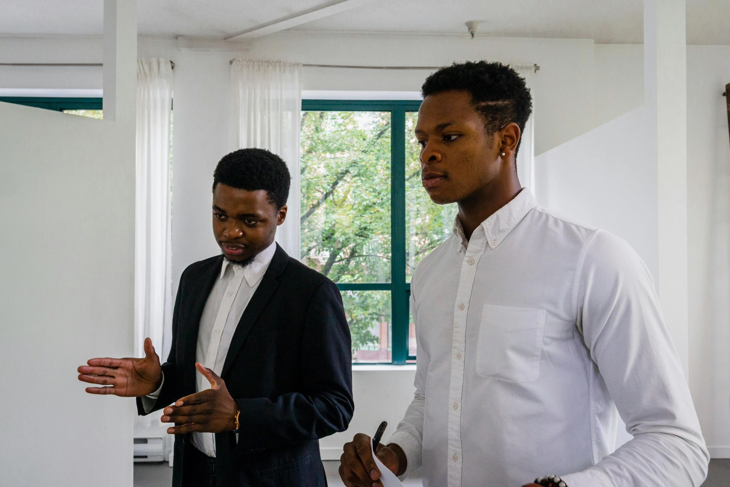 two men standing next to each other in a room, pexels contest winner, african canadian, facing sideways, in the office, wearing a white button up shirt