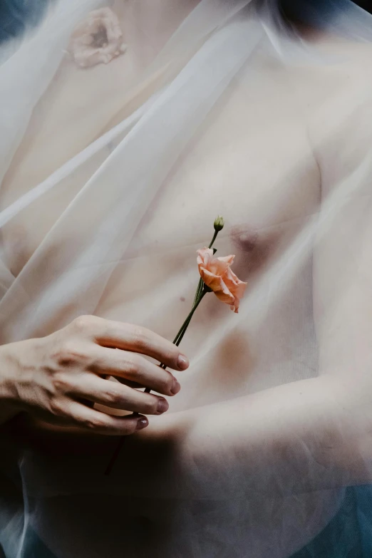 a woman holding onto a flower wearing a veil