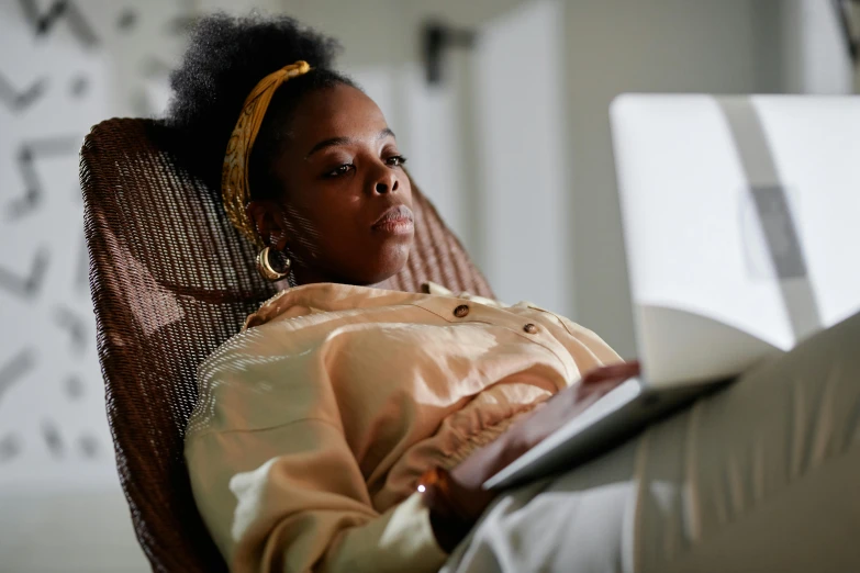 a woman sitting in a chair with a laptop, by Lily Delissa Joseph, trending on pexels, renaissance, with brown skin, sleepy, 4k), performing