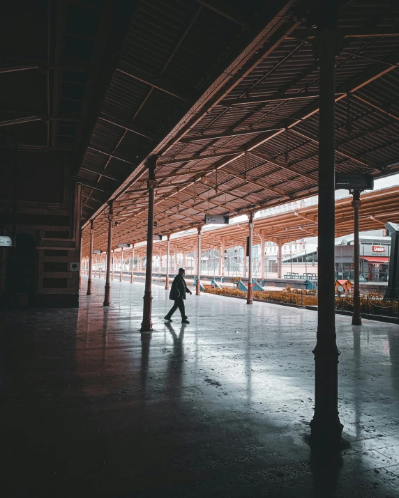 a person walking through an empty train station, inspired by Steve McCurry, unsplash contest winner, indore, square, rain aesthetic, lgbtq