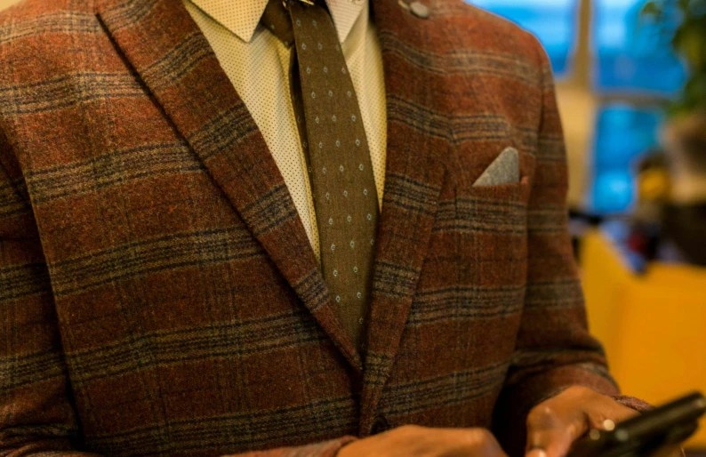 a man with a suit jacket holding two cell phones