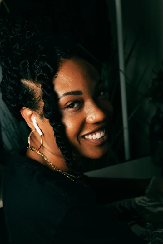 a woman sitting in front of a laptop computer, an album cover, by Stokely Webster, pexels contest winner, smiling slightly, black hair in braids, headshot profile picture, curls