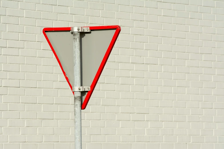 a street sign in front of a white brick wall, inspired by Charles Hinman, unsplash, postminimalism, flat triangles, silver red, ignant, traffic signs