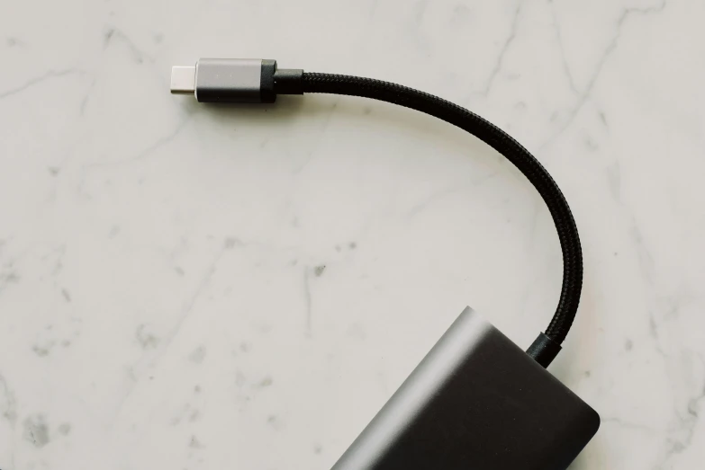 a close up of a cable connected to a device, by Carey Morris, trending on pexels, minimalism, rectangle, black, vapor, on a table