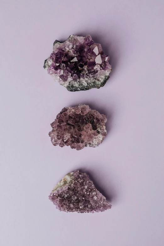 three pieces of amethorate on a purple background, trending on pexels, mineral collections, sarah cliff, made of crystal, on a pale background