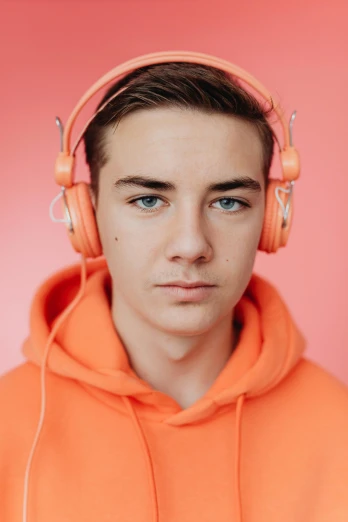 a man in an orange hoodie with headphones on, by Matthias Stom, trending on pexels, antipodeans, androgynous face, pink hue, portrait a 1 5 - year - old boy, 15081959 21121991 01012000 4k