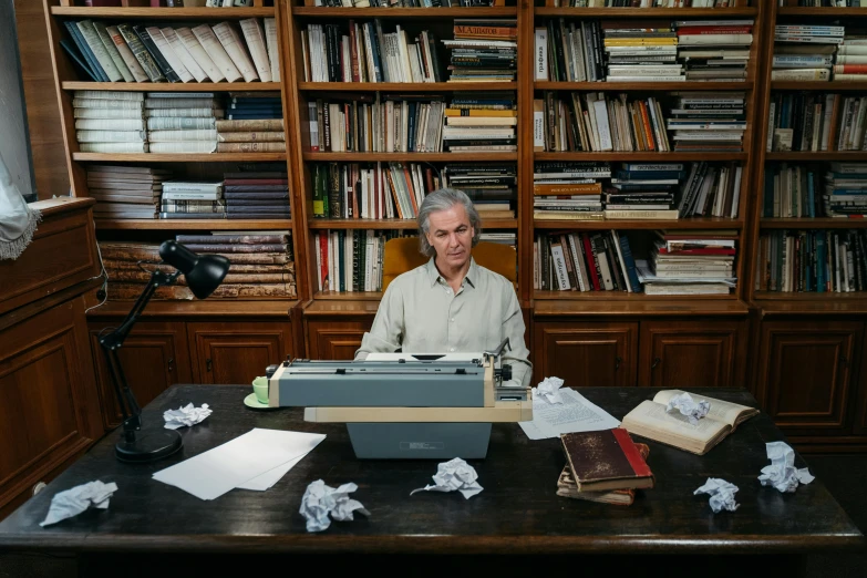 a man sitting at a desk in front of a typewriter, yann arthus - bertrand, jerome powell, ignant, papers and tomes