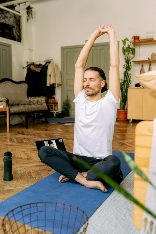 a man is sitting in the middle of a room with his arms in the air