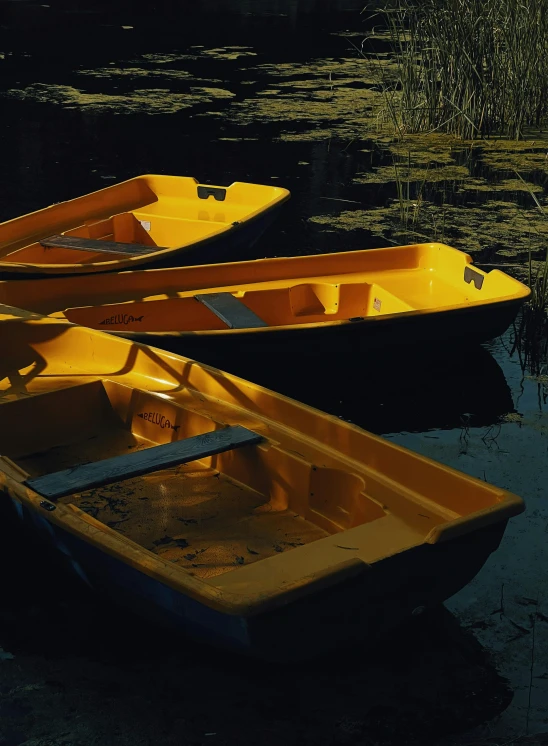 a group of yellow boats floating on top of a lake, pexels contest winner, tonalism, on a dark swampy bsttlefield, dingy lighting, glossy surface, dark. no text