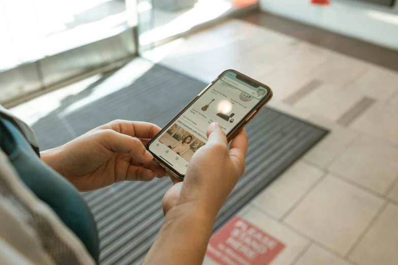 a close up of a person holding a cell phone, a picture, trending on pexels, exiting store, brown, at checkout, sitting down