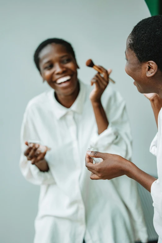 a couple of women standing next to each other, by Matija Jama, trending on unsplash, happening, putting makeup on, wearing white pajamas, smiling and dancing, chocolate