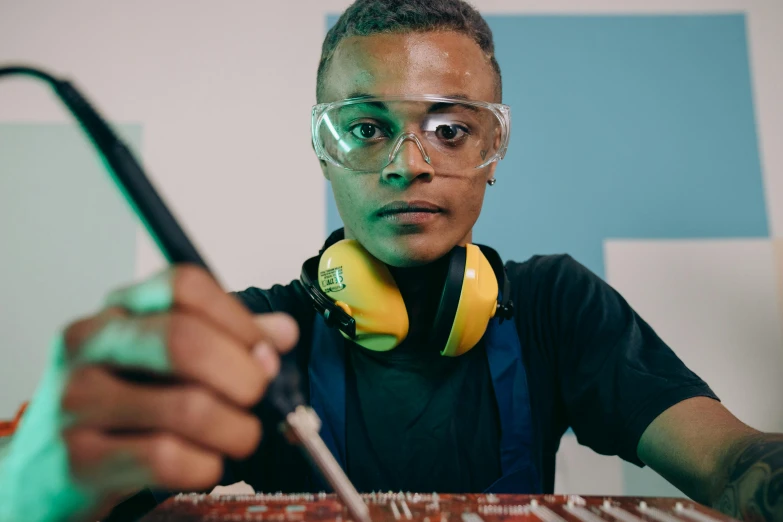 a close up of a person with headphones and a keyboard, inspired by Afewerk Tekle, smoking soldering iron, stood in a lab, teenage engineering moad, teal electricity