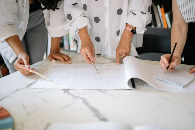 three people working on a plan while one person writes in a notebook