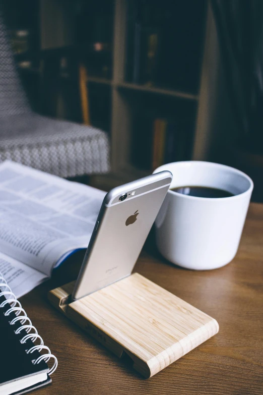 an open book sitting on top of a wooden table next to a cup of coffee, a picture, trending on unsplash, modernism, corporate phone app icon, light wood, cell phone photo, 9 9 designs