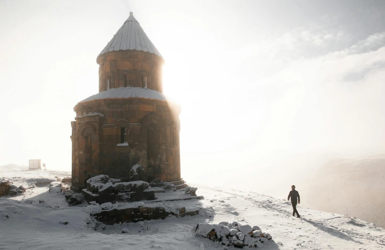 a person standing on top of a snow covered hill, an album cover, by Arthur Sarkissian, pexels contest winner, romanesque, temple, aykut aydogdu, assyrian, winter photograph