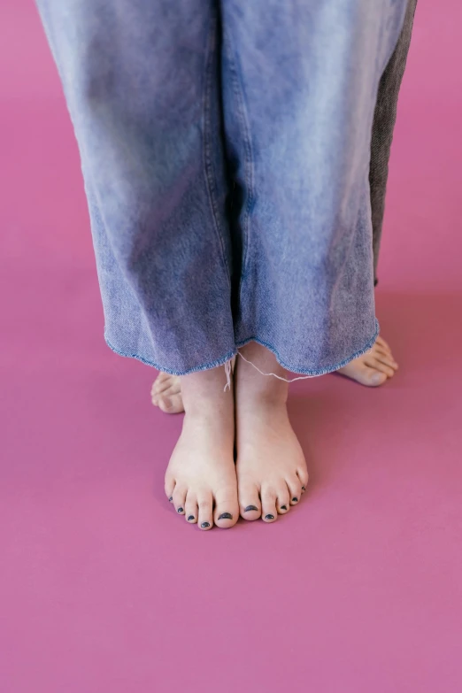 a persons feet wearing jeans with their toes tied down