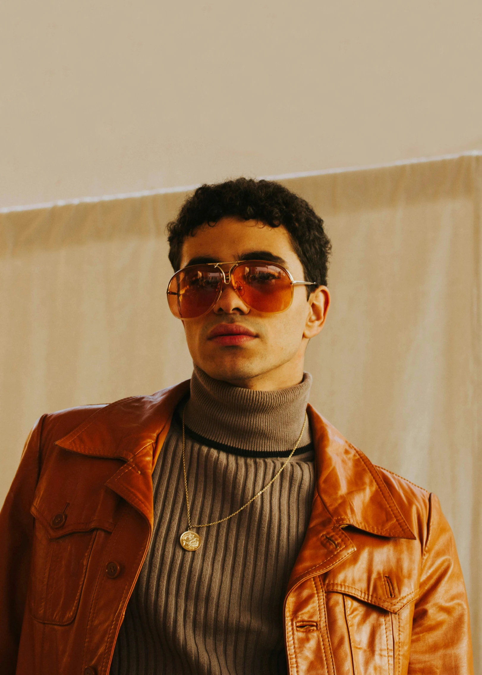 a man in a tan leather jacket and glasses