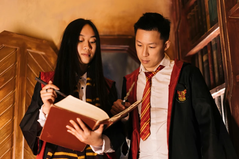 a couple of people standing next to each other, pexels contest winner, academic art, hogwarts gryffindor common room, asian descent, holding grimoire, wearing headmistress uniform