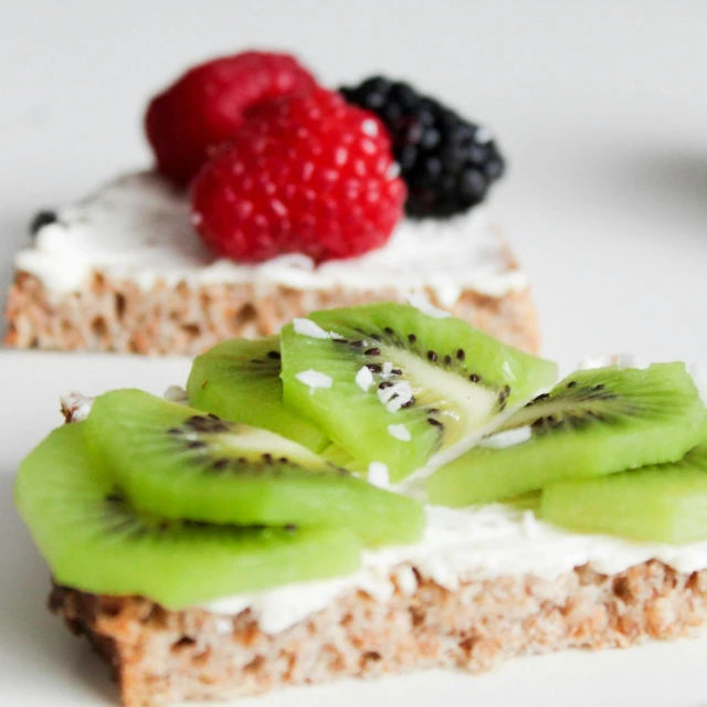 two pieces of bread topped with kiwi and raspberries, by Anna Haifisch, pexels, hurufiyya, marshmallow graham cracker, red green white black, low detail, white