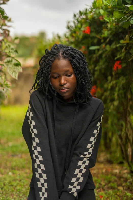 a woman sitting on the ground in front of a bush, an album cover, pexels contest winner, box braids, wearing a black hoodie, sad man, unmistakably kenyan