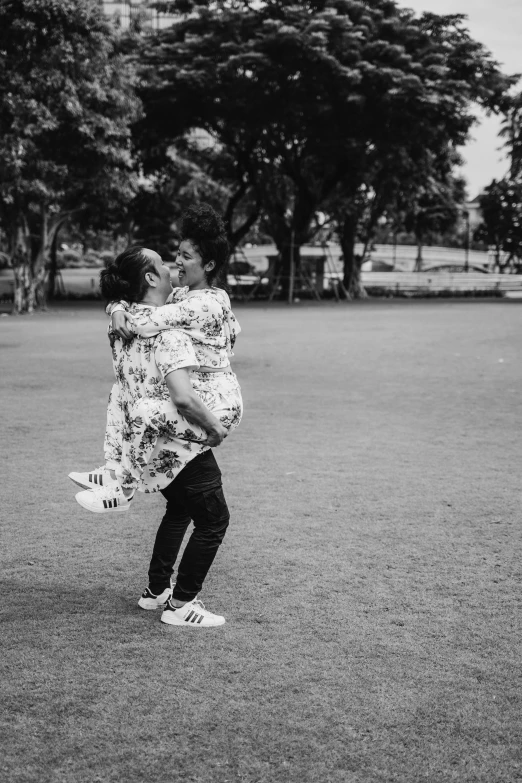 a black and white photo of a woman throwing a frisbee, by Basuki Abdullah, happening, hugging each other, instagram picture, on a green lawn, lovers