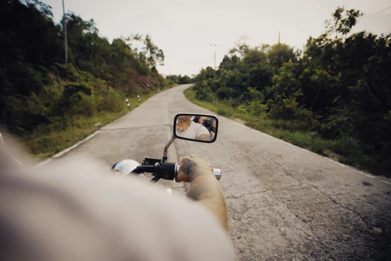 a man on a motor cycle taking a picture of himself in a rear view mirror