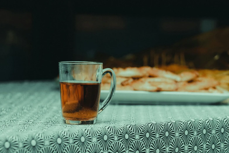 a glass of tea sitting on top of a table, inspired by Elsa Bleda, pexels, moroccan, lit from the side, mead, battered