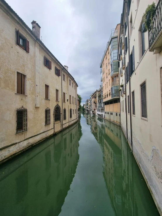 a river running through a city next to tall buildings, by Alessandro Allori, pexels contest winner, renaissance, canal, thumbnail, low quality photo, green alleys