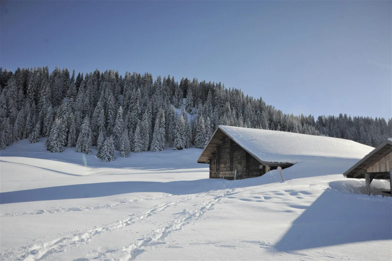 a couple of cabins sitting on top of a snow covered slope, inspired by Peter Zumthor, pexels contest winner, thumbnail, clear blue skies, barn, conde nast traveler photo