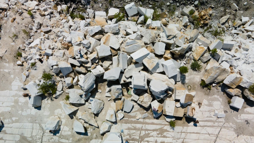 a pile of rocks sitting on top of a dirt field, a marble sculpture, inspired by Filip Hodas, unsplash, aerial view, carrara marble, 2000s photo, marble slabs