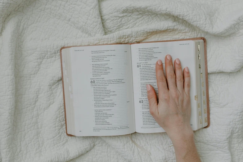 a person is reading a book on a white bed